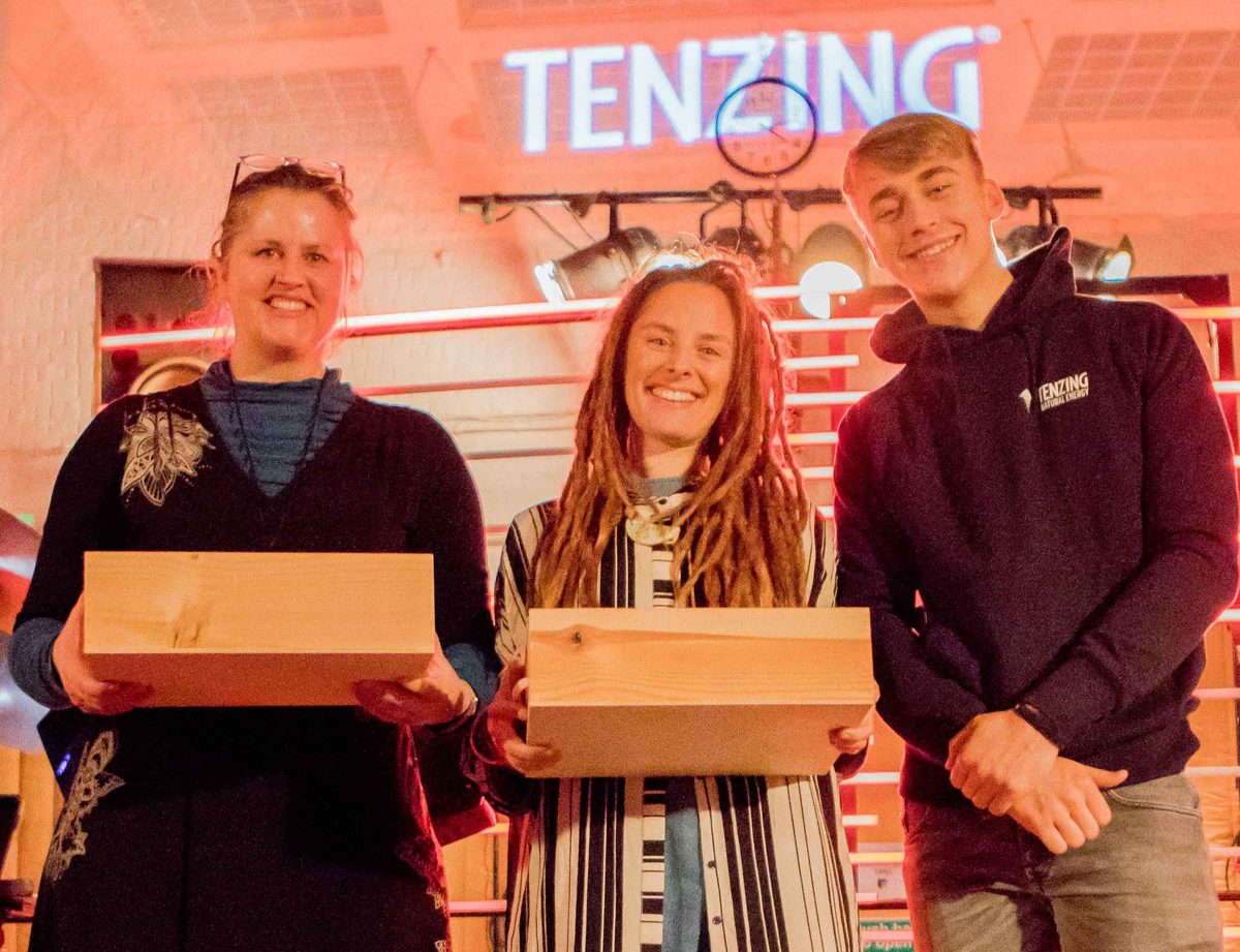 Winners holding plaques on stage under an illuminated Tenzing sign at the Abbey Road Studios hackathon in London