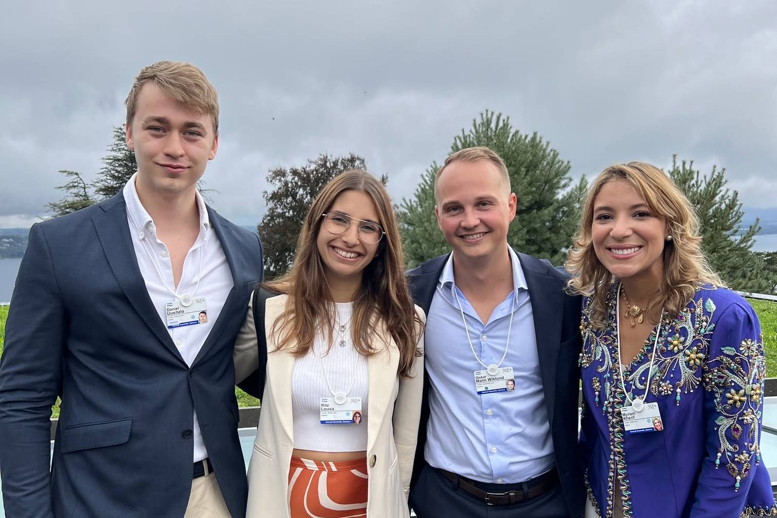 Daniel Uusitalo with three fellow Global Shapers wearing summit badges on a terrace above Lake Geneva