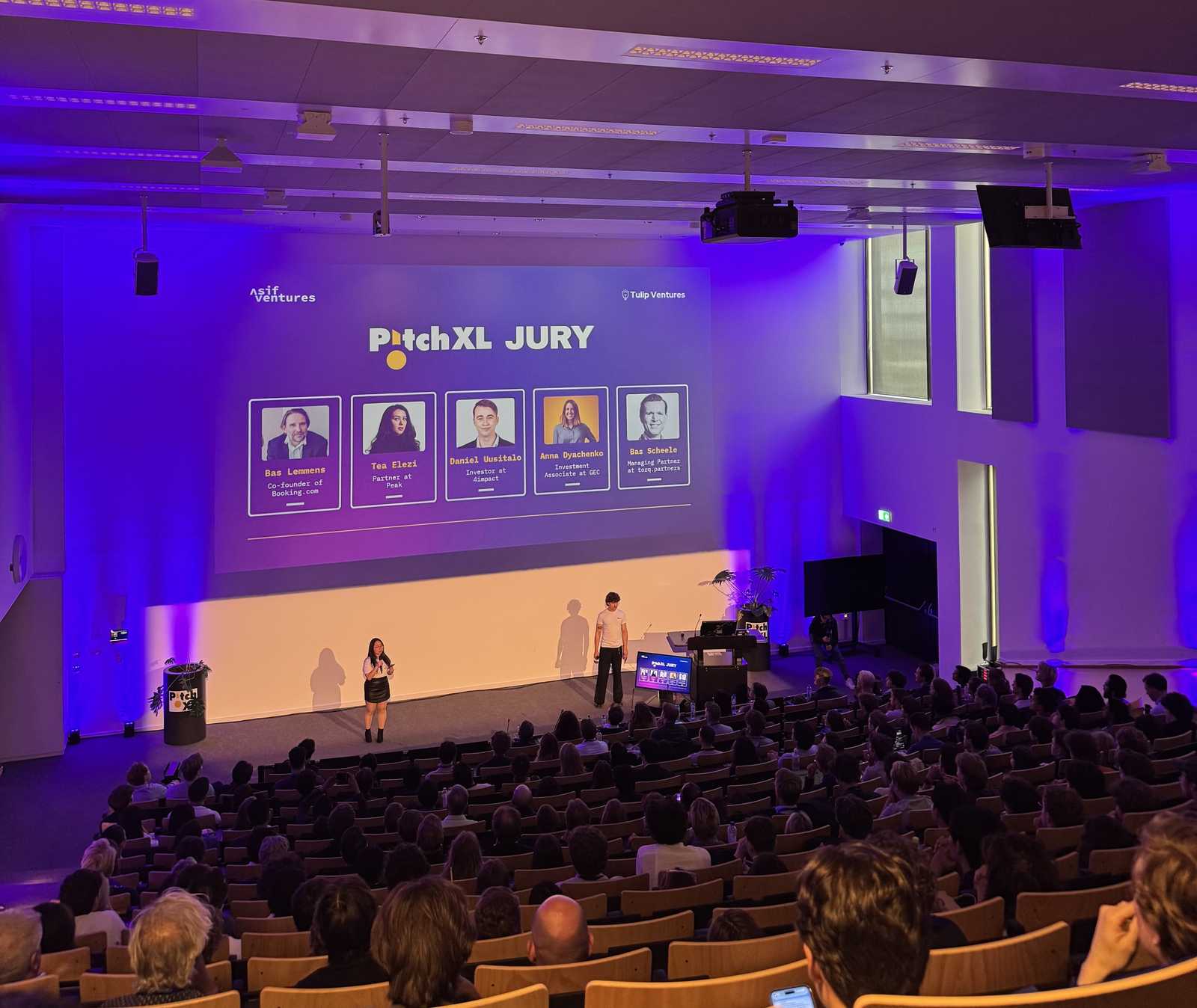 PitchXL jury slide naming Daniel Uusitalo of 4impact projected above a full auditorium at the Asif Ventures final in Amsterdam