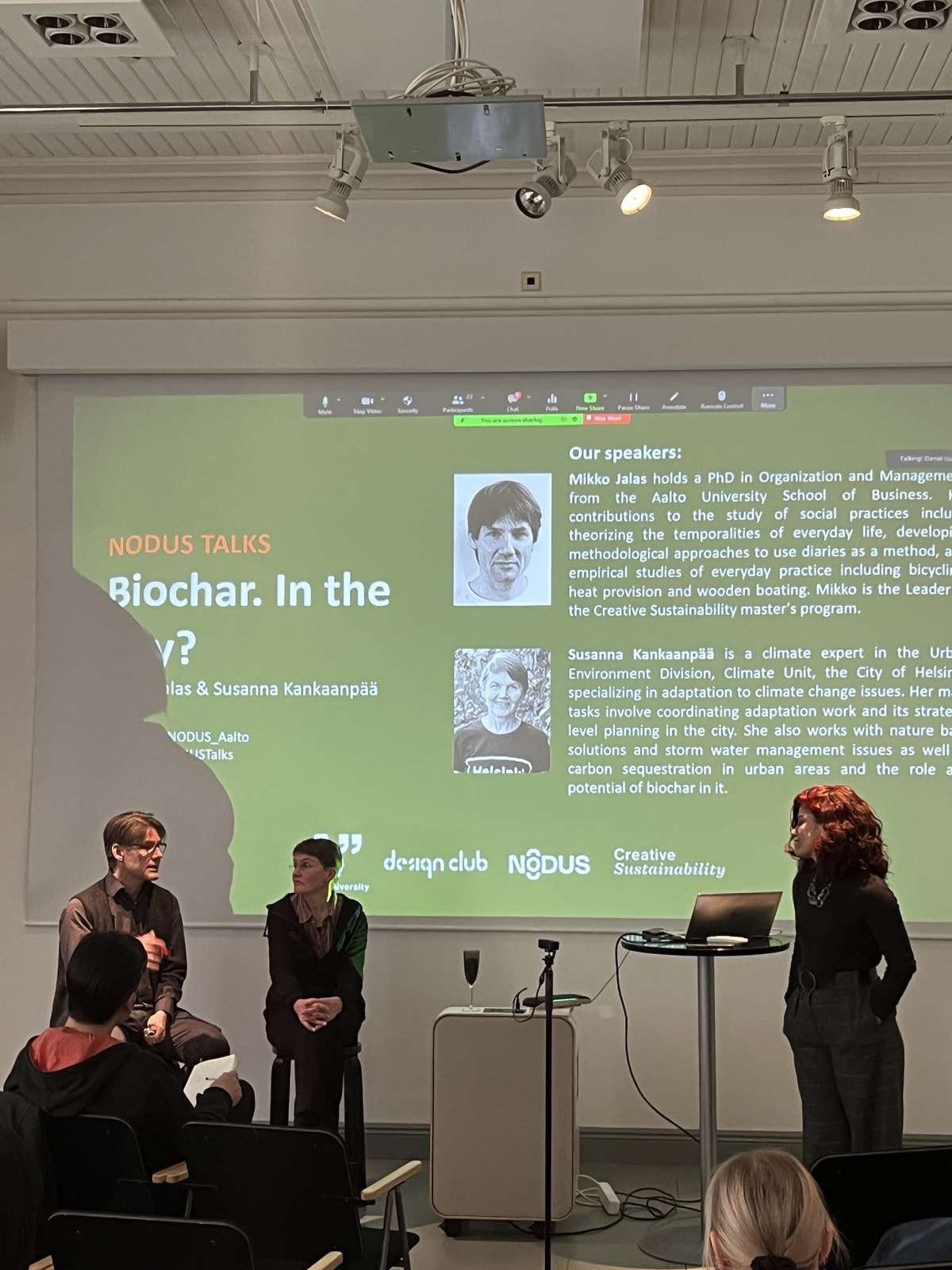 Speakers beside a projected Nodus Talks slide on biochar at an Aalto University session in Helsinki